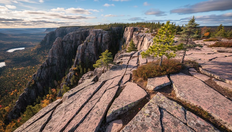 A wide view of Canadian Shield granite ridges and cliff bands with a small hiking figure on the route